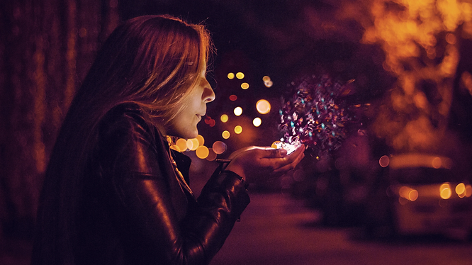 a girl blowing sparklets at night